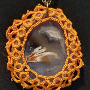 Agate pendant surrounded by intricate orange lace