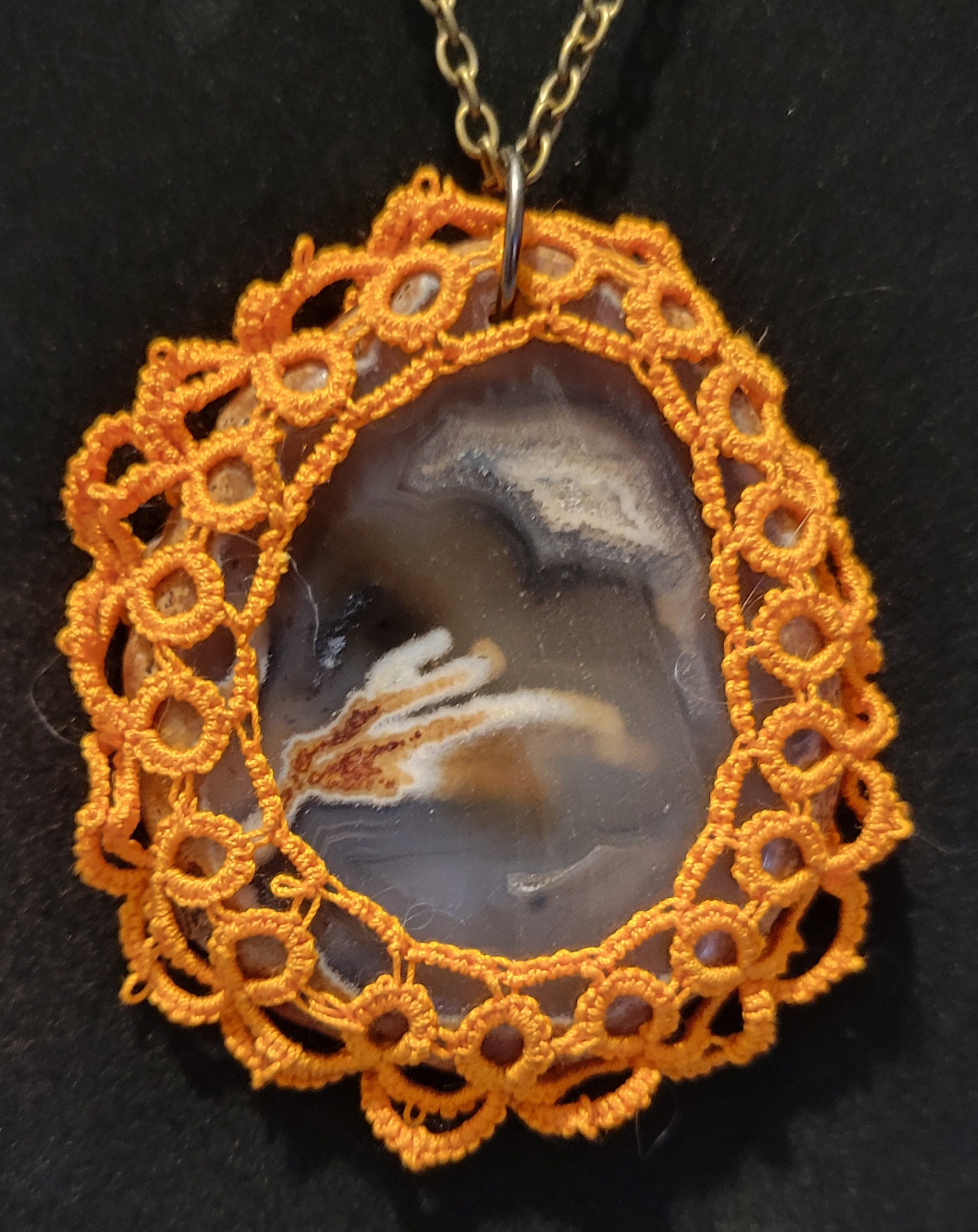 Agate pendant surrounded by intricate orange lace
