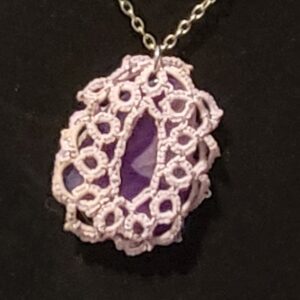 Hand-tatted lavender lace pendant necklace featuring a purple agate stone on a 20-inch silver-tone chain against a black background.