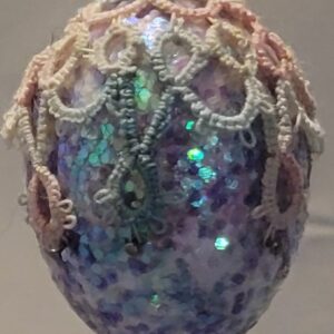Small iridescent blue and lavender ornament decorated with delicate pastel hand-tatted lace trim.