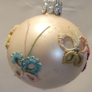 Pearl ornament decorated with small pastel hand-tatted butterflies in aqua, pink, lavender, and green.