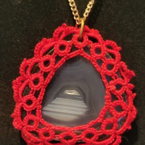 Teardrop-shaped agate pendant framed with intricate red crochet