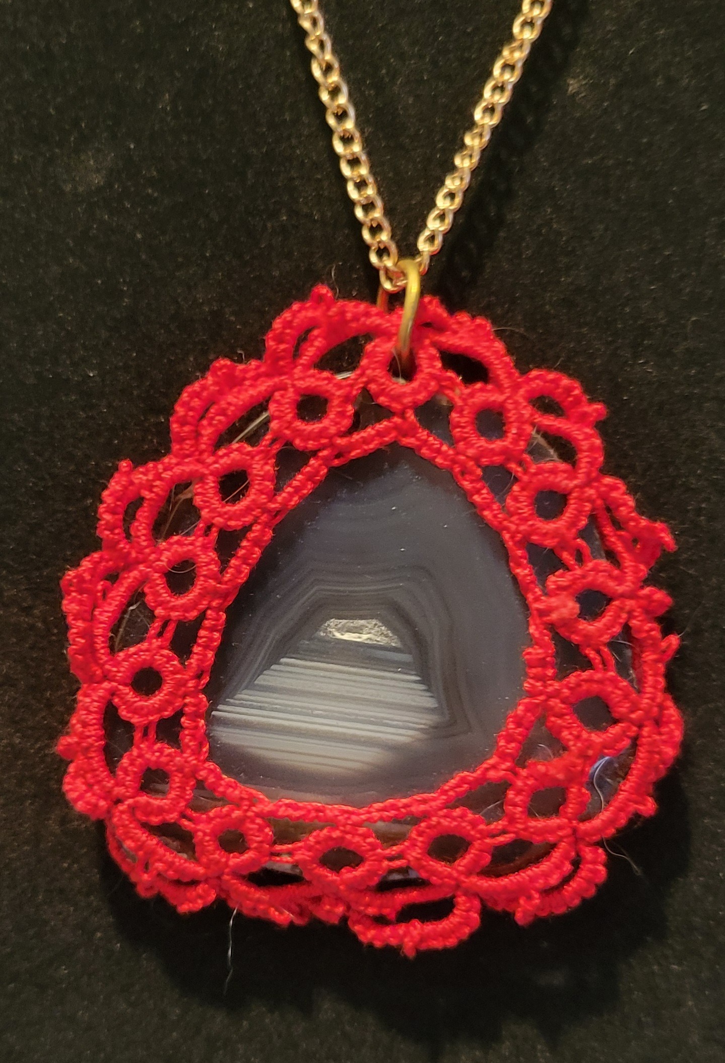 Teardrop-shaped agate pendant framed with intricate red crochet
