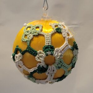 Golden yellow ornament decorated with floral hand-tatted lace in white, mint green, and dark green accents.