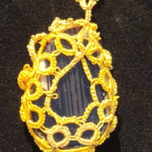 Yellow lace surrounds a clear, teardrop-shaped pendant on a black background