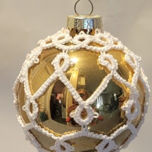 Gold reflective ornament covered with intricate white hand-tatted lace in an elegant lattice pattern.