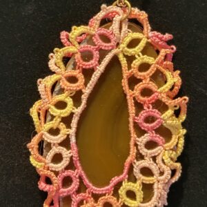 A colorful, intricately knotted lace pendant encases a smooth