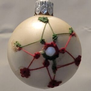 Small pearl ornament decorated with delicate red and green hand-tatted holly and berry lace accents.