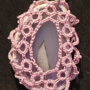 Lace-covered pendant showcasing a smooth stone with a cutout