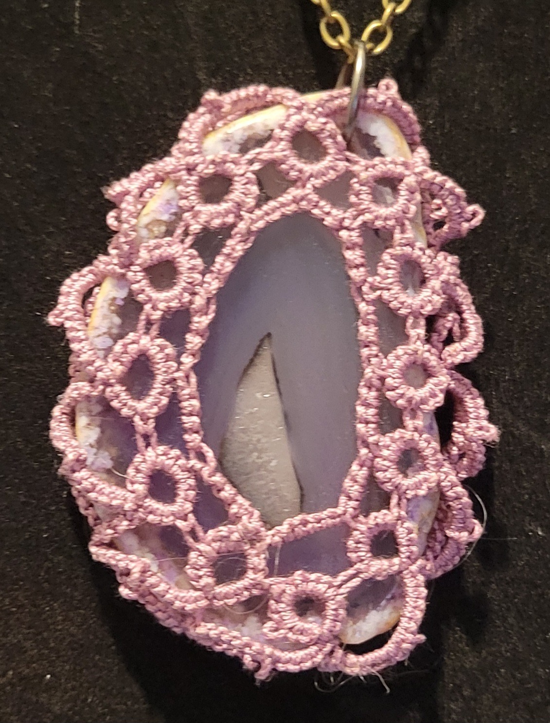 Lace-covered pendant showcasing a smooth stone with a cutout