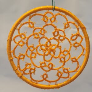 Hand-tatted marigold orange mandala with intricate floral lacework suspended inside a matching wrapped 4-inch hoop.