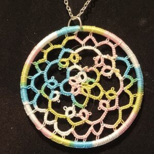 Round pastel multicolor hand-tatted lace medallion pendant on an 18-inch silver-tone chain displayed against a black background.