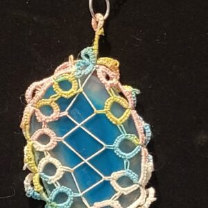 Blue agate pendant wrapped in pastel hand-tatted lace on a 20-inch silver-tone chain displayed against a black background.
