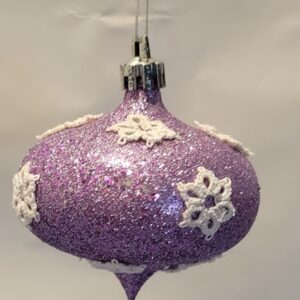 Lavender glitter finial ornament decorated with delicate ivory hand-tatted snowflake motifs.