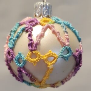 Small pearl-white ornament covered with pastel rainbow hand-tatted lace in delicate looping patterns.
