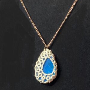 Blue agate pendant wrapped in ivory hand-tatted lace on a 20-inch chain displayed against a black jewelry bust.