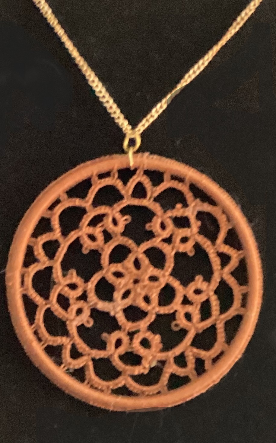 Round chestnut brown hand-tatted lace medallion pendant on a 20-inch chain displayed against a dark background.