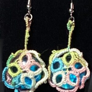 Handmade pastel rainbow tatted earrings with blue iridescent cabochons and silver-tone hooks against a black background.