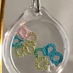 Clear acrylic keychain featuring pastel tatted flower designs in blue, pink, and green with silver key ring.
