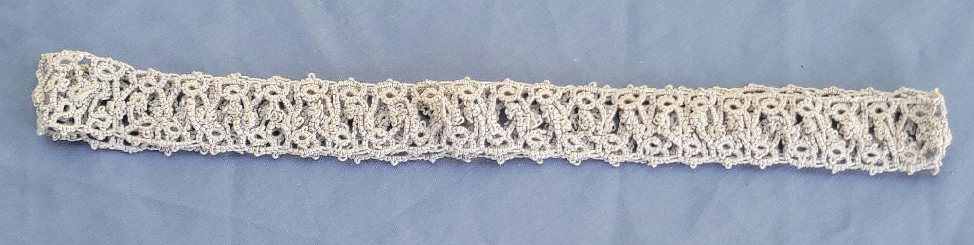 Silver-white hand-tatted lace hat band with intricate repeating pattern