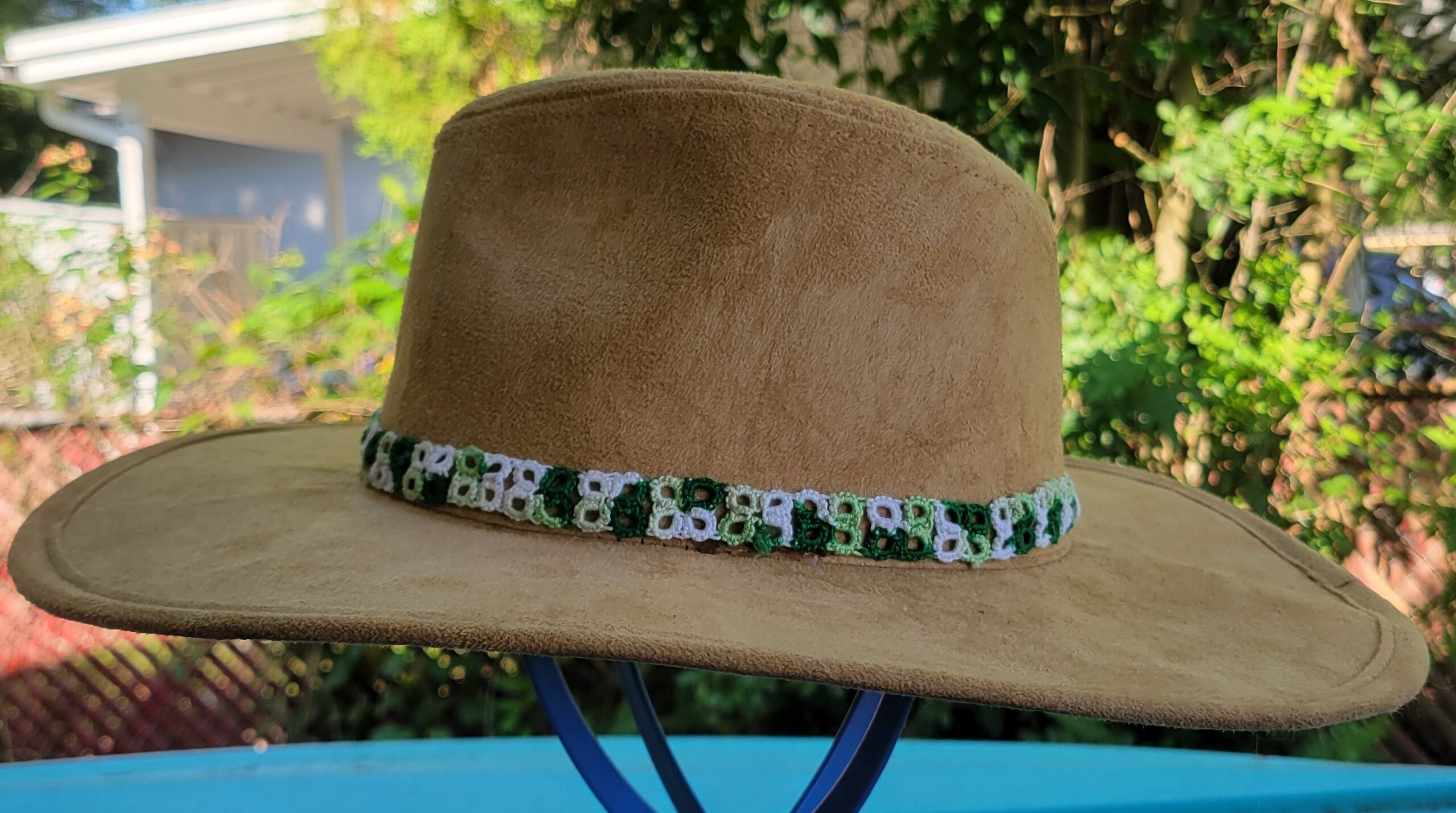 Green, light green, and white hand-tatted lace hat band displayed around a tan wide-brim hat; hat not included