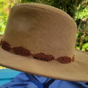 Brown hand-tatted leaf hat band displayed around the crown of a tan hat