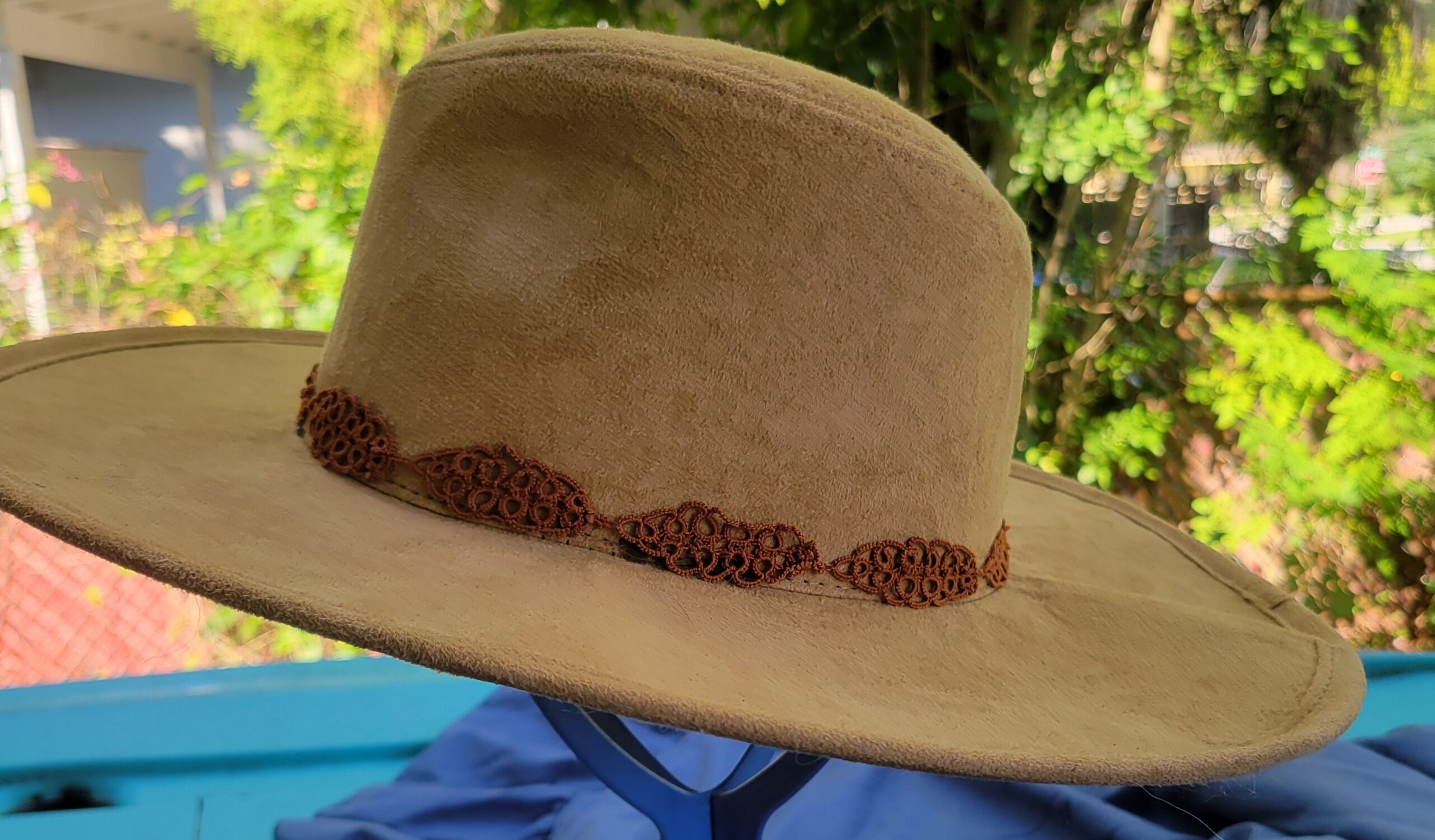 Brown hand-tatted leaf hat band displayed around the crown of a tan hat