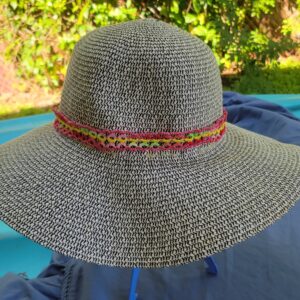 Colorful pink yellow green and red hand-tatted lace hat band on a black and white woven hat