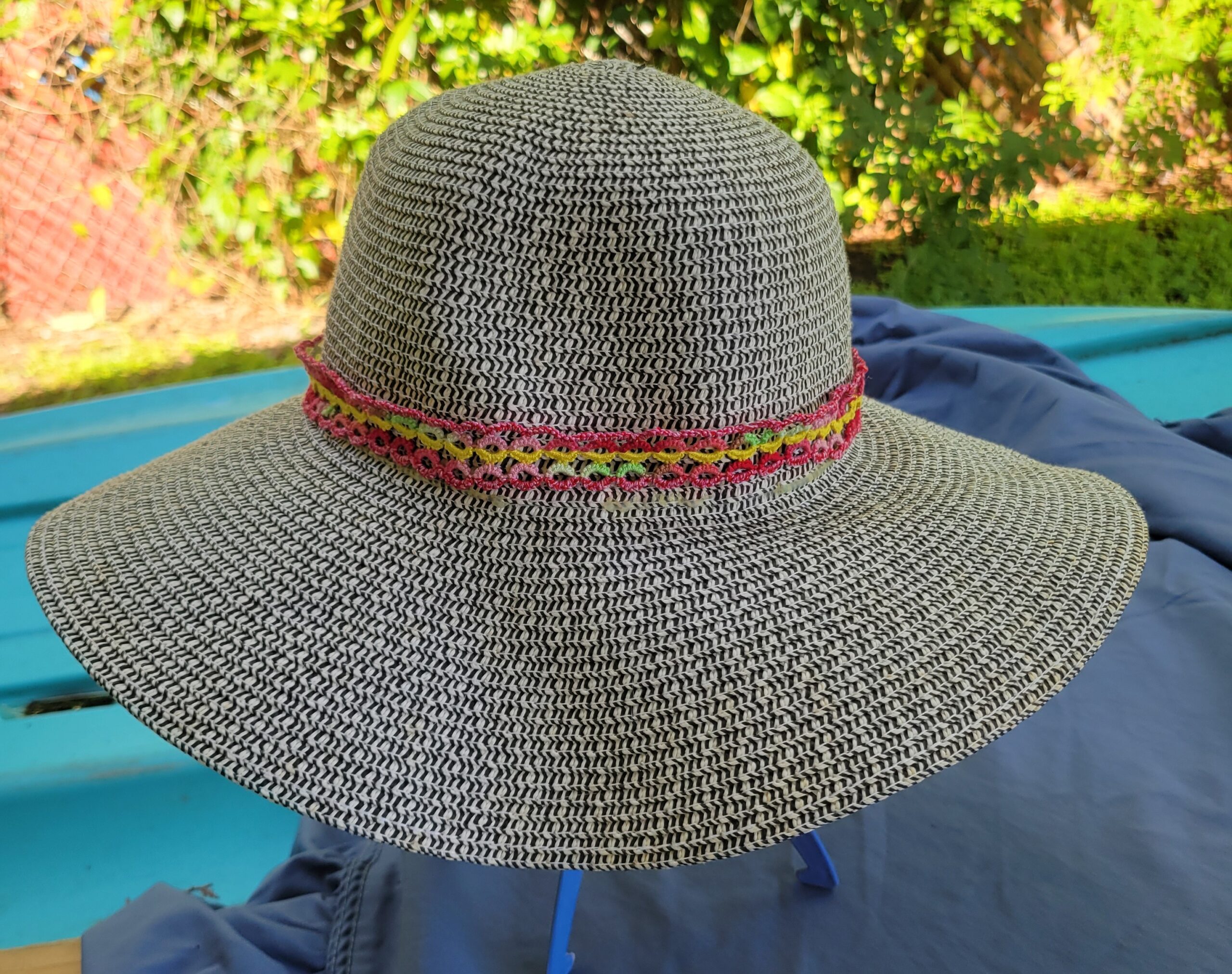 Colorful pink yellow green and red hand-tatted lace hat band on a black and white woven hat