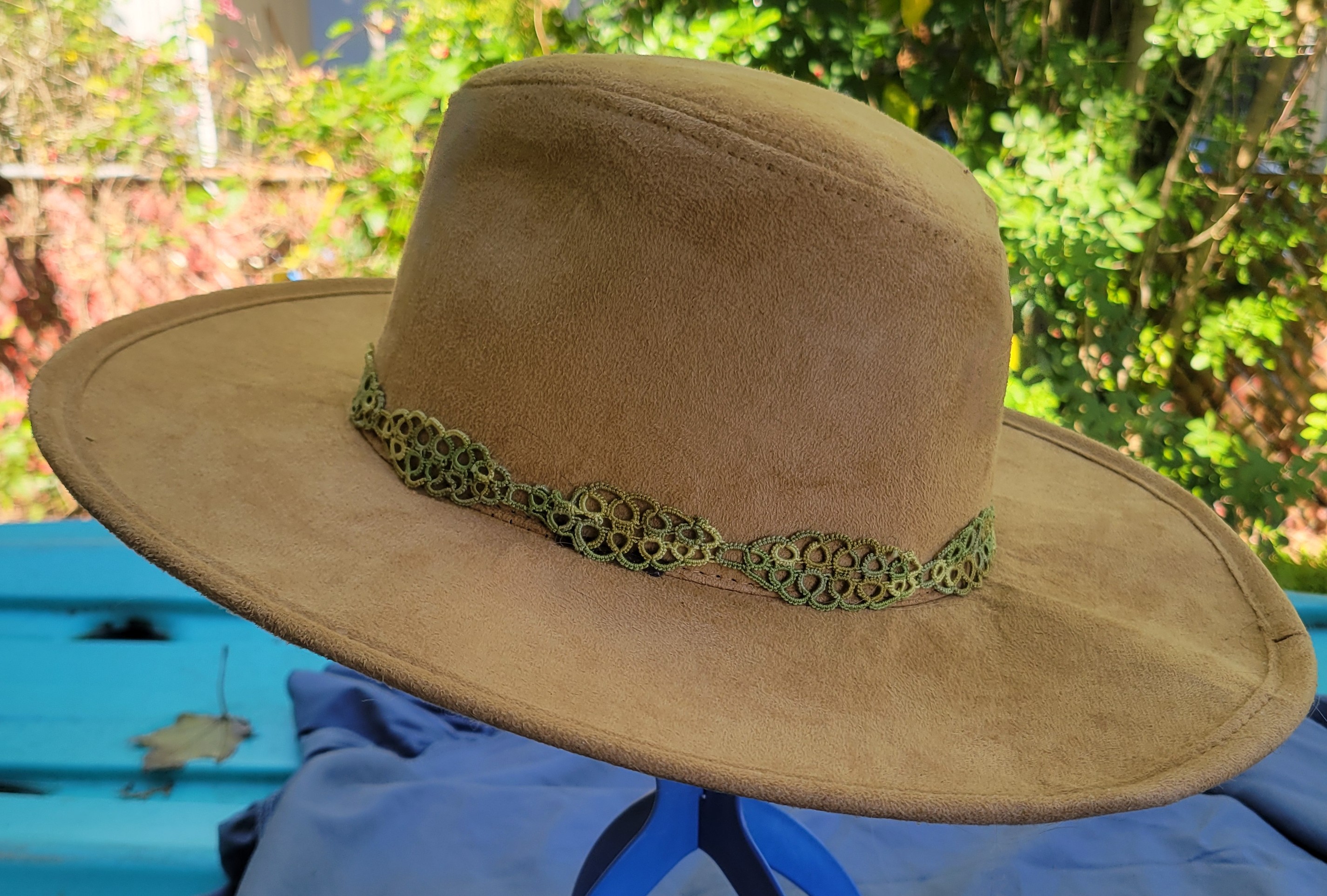 Olive green hand-tatted lace hat band displayed on a tan hat