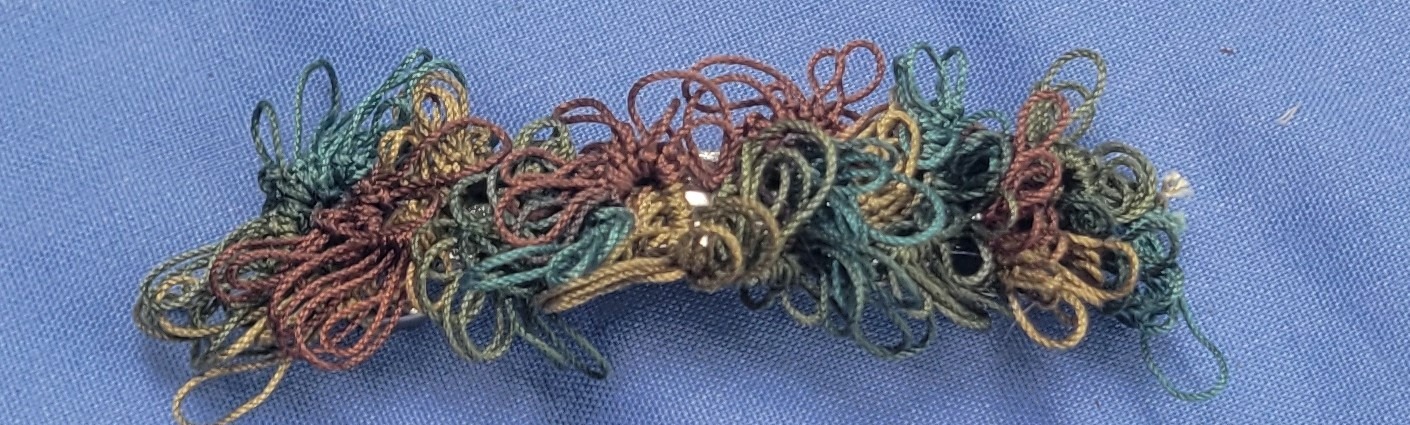 Rustic hand-tatted lace barrette with layered floral motifs in forest green, olive, brown, copper, and muted gold, approximately 2.75 inches long.