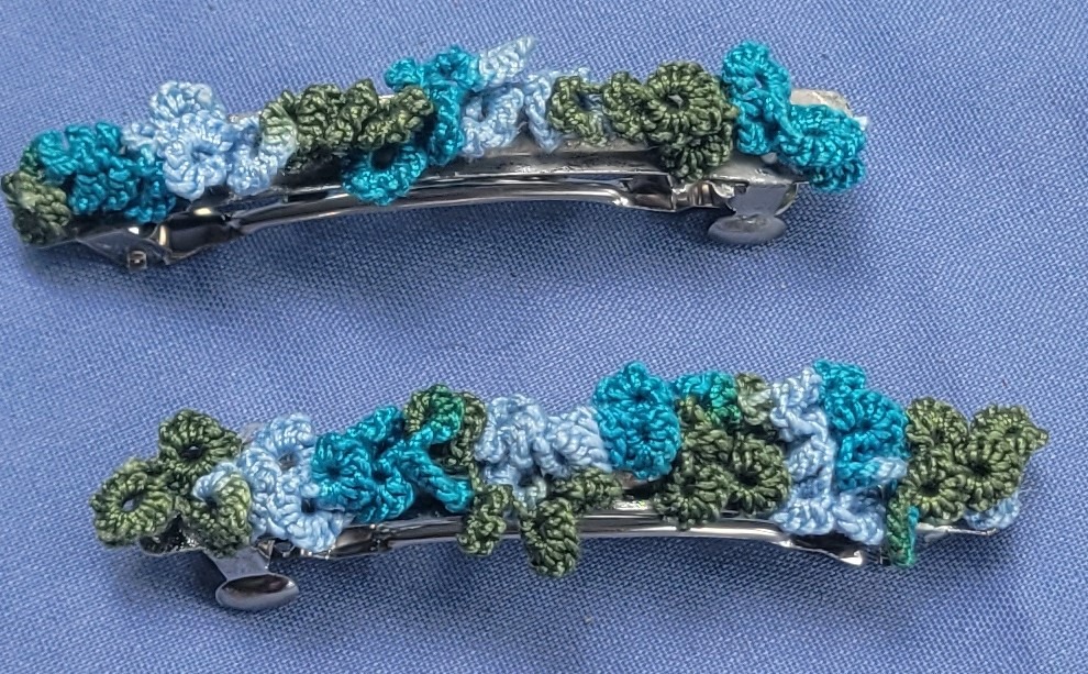 Set of two hand-tatted floral lace barrettes in teal, blue, pale blue, and sage green, each measuring approximately 2.75 inches long.